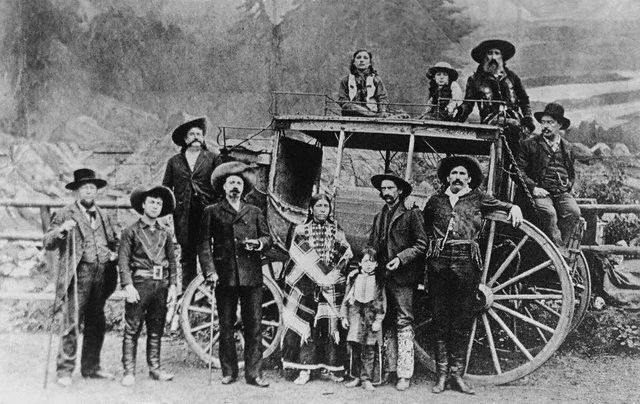 Cowboys and Indians standing in front of carriage 